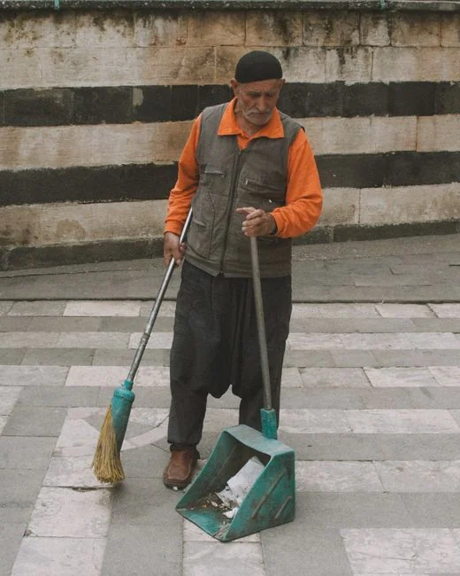 Two women in red overalls vacuuming and sweeping a modern living room.